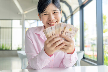 Money, Cash, Wealth, Happy Asian woman holding Thai baht banknotes, showing wealth, success, and financial happiness, close-up