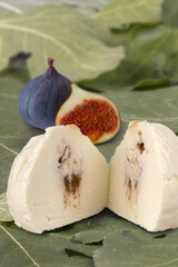 Fig flavoured goats cheese with figs on a background of fig leaves and fig trees