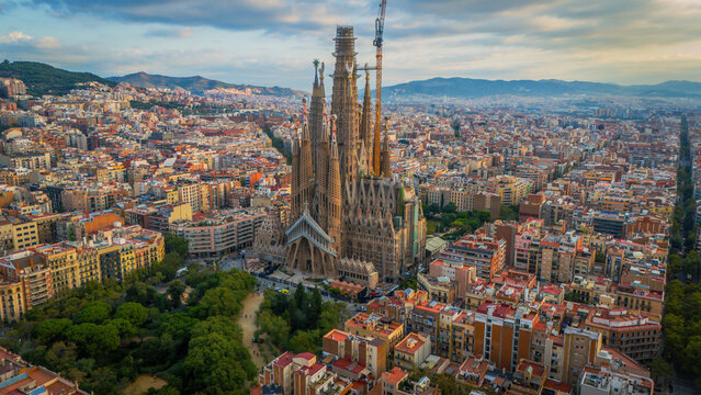 Aerial view of the Sagrada Familia's spires piercing the sky, a symphony of stone amidst the urban tapestry, Barcelona, Catalunya, Spain.