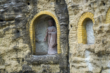 Fototapeta premium Buddha statue in arched niche carved in rocky wall
