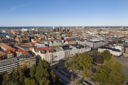 Aerial view of the St. Peter's Church towering over the city with the Turning Torso skyscraper in the distance, Gustav Adolfs Torg square and green trees, Malmo, Sweden.