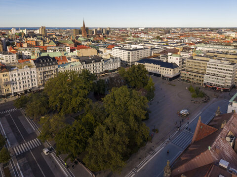 Aerial view of the vibrant Gustav Adolf Torg square, with its lush green trees contrasting against the surrounding buildings, a captivating blend of nature and architecture, Malmo, Sweden.