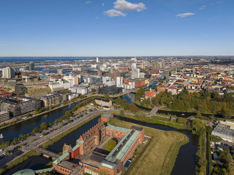 Aerial view of the Malm&Atilde;&para;hus Castle with its red brick walls and green roofs, embraced by the serene canals reflecting the clear blue sky, Malmo, Skane County, Sweden.