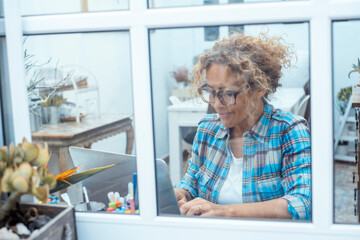 Woman working on a laptop at home, focused and productive while sitting on sofa or at table, symbol of remote work, digital lifestyle, freelance work, modern life and home office
