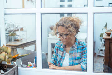 Woman working on a laptop at home, focused and productive while sitting on sofa or at table, symbol of remote work, digital lifestyle, freelance work, modern life and home office
