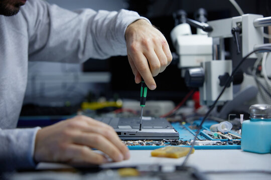 A technician is carefully repairing a circuit board with precision tools in a workshop - Powered by Adobe