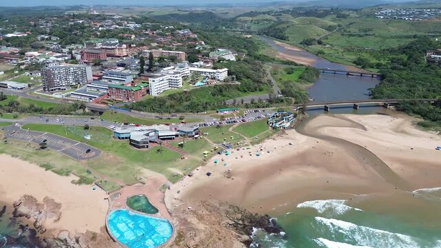 Camera panning left to right the beach and tidal pool and the rolling green hills of the South Coast of Kwazulu-Natal the coastal town of Scottburgh Aerial 4K video