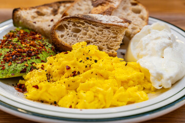 brunch dish with avocado, egg scramble, bread and yogurt