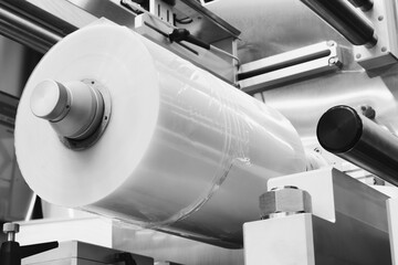 Automatic polyethylene plastic bag production machine with lighting effect. Close-up of the roller of the plastic bag production machine in the light blue scene. product packaging concept