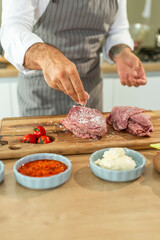 Chef sprinkling salt on fresh red meat in a modern kitchen