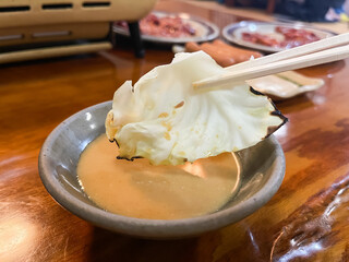 焼いたキャベツを味噌タレに付けている。焼肉屋での風景。