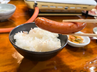 焼いたウインナーとご飯と一緒に食べる。焼肉屋の風景。