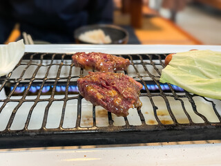 焼肉屋の風景。焼いてる味噌タレの付いた牛ロース肉。