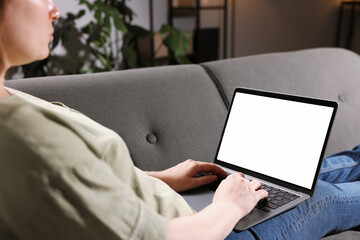 Woman working with laptop on sofa indoors, closeup. Mockup for design
