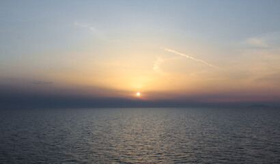 Scenic sunset over the sea with orange sky and calm water surface.