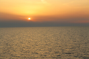 Beautiful golden sunset over calm sea horizon, tranquil ocean landscape.