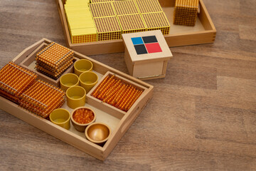 Alternative Montessori teaching materials. Wooden tray with gold beads for learning mathematics and wooden binomial cube. Development of logical thinking and imagination.