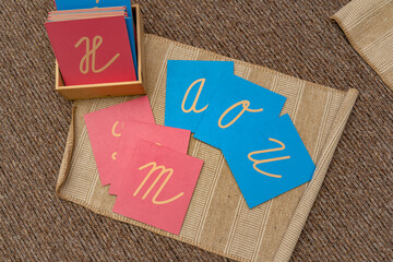 Montessori writing materials. Sensory materials, pink and blue letter cards on a learning mat. Develops muscle memory, understanding of shape and hand movements in elementary school.