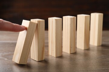 Risk. Woman pushing wooden blocks at table, closeup