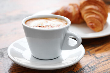 Aromatic coffee and tasty croissants on wooden table, closeup
