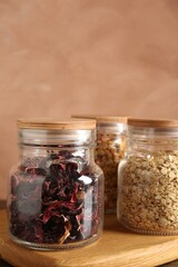 Glass jars with different products on wooden table, closeup