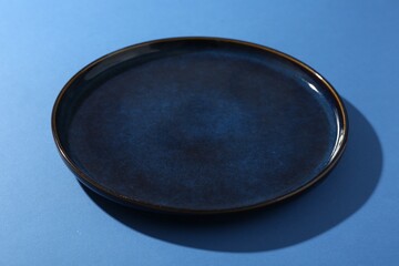 Stylish ceramic plate on blue background, closeup