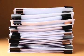 Many documents with binder clips on brown background, closeup