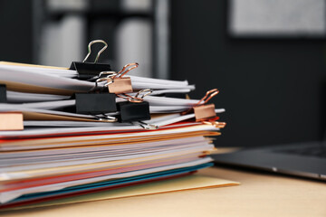 Many folders with documents and laptop on wooden desk, closeup. Space for text