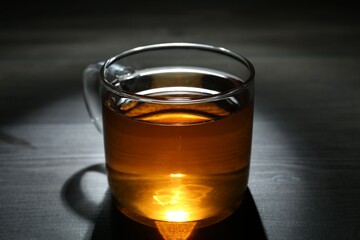 Aromatic black tea in glass cup on wooden table, closeup