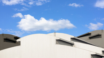 Modern industrial warehouse architecture with curved roof and blue sky