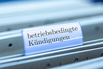 Schild mit der Aufschrift BETRIEBSBEDINGTE KÜNDIGUNGEN an einem Hängemappenregister