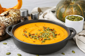 Delicious pumpkin soup served on grey table, closeup