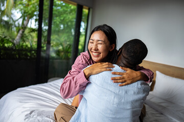 Happy and diverse couple sharing a joyful moment at home, embracing and smiling together