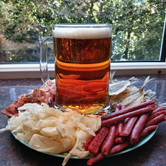 A glass of beer and dried seafood as an appetizer to go with the drink. Squid, fish, and caviar. Delicious and appetizing food that pairs perfectly with a refreshing beer.