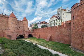 
The defensive walls of Warsaw's old town. Brick walls, townhouses in the background. The capital of Poland. Podwale Street. The Barbican.