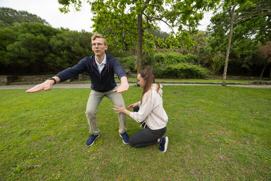 Young man performing squat exercise with woman coaching outdoors - Powered by Adobe