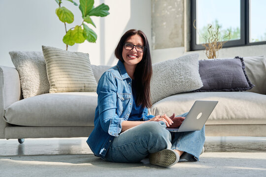 Portrait of young beautiful positive woman with laptop sitting at home