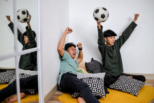Excited Young Men Cheer Watching Soccer Game With Ball