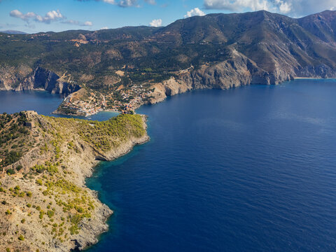 Aerial view of Assos village clings dramatically to the peninsula, its terracotta roofs a warm contrast to the deep blue Ionian Sea, Asos, Cephalonia, Greece.