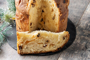 Traditional Italian Panettone on wooden table and christmas tree background
