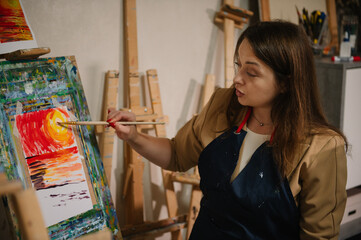 Woman drawing brush on easel. Teacher learn children to draw pictures in an art lesson. Painting in workshop. Artist explains how to mix and combine colors. Education, learning concept. Closeup.
