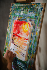 Artist paints nature with his hand and brush in art class. Education and learning concept. People drawing with brush on easel. Girl mixing and combining colors. Woman painting in a workshop. Closeup.
