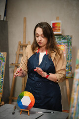 Woman drawing brush on easel. Teacher learn children to draw pictures in an art lesson. Painting in workshop. Artist explains how to mix and combine colors. Education, learning concept. Closeup.