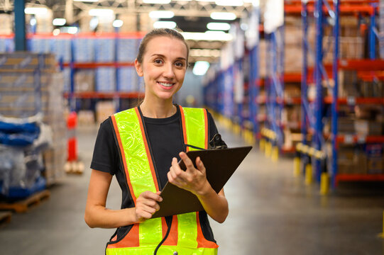 Factory worker woman holding clipboard while checking the stock order details and goods supplies in the workplace warehouse.