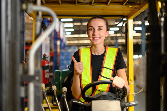 Young female warehouse worker driving a forklift at shipping warehouse. Industrial engineer woman in safety vest drives reach stacker to lift cargo box at freight cargo warehouse port.