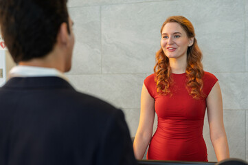 Female receptionist at front desk for reservations, booking room or check-ins. Welcome and friendly hotel staff.