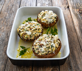 Stuffed portobello mushrooms in baking dish ready for baking on wooden table