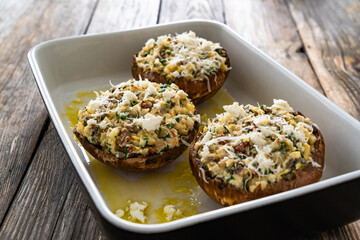 Stuffed portobello mushrooms in baking dish ready for baking on wooden table
