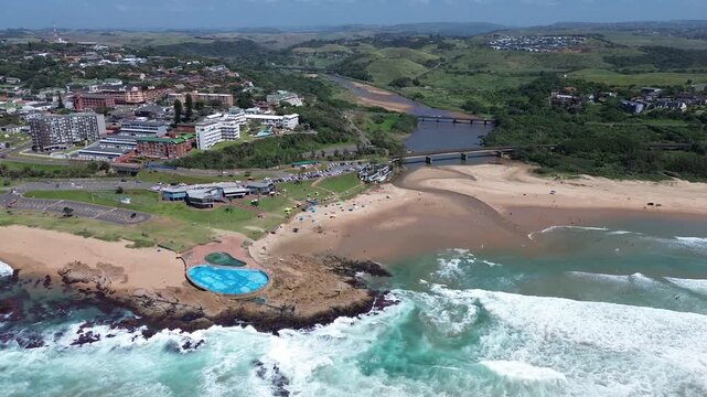 Camera moving right to left from the beach and tidal pool towards the coastal town of Scottburgh on the South Coast of KwaZulu-Natal, Aerial 4K video.