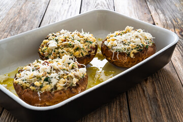 Stuffed portobello mushrooms in baking dish ready for baking on wooden table